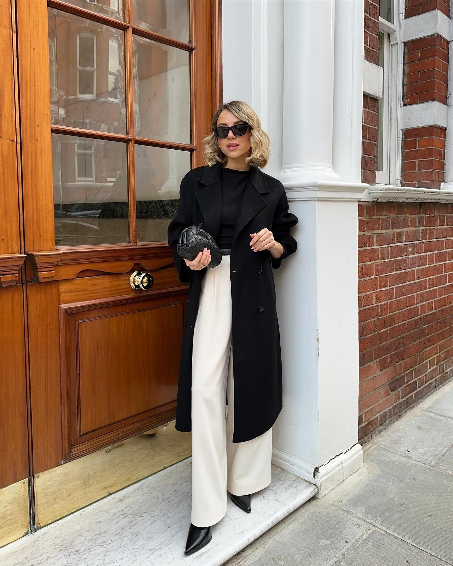 Bone White Flowy Pants with Tailored Black Overcoat and Woven Leather Clutch