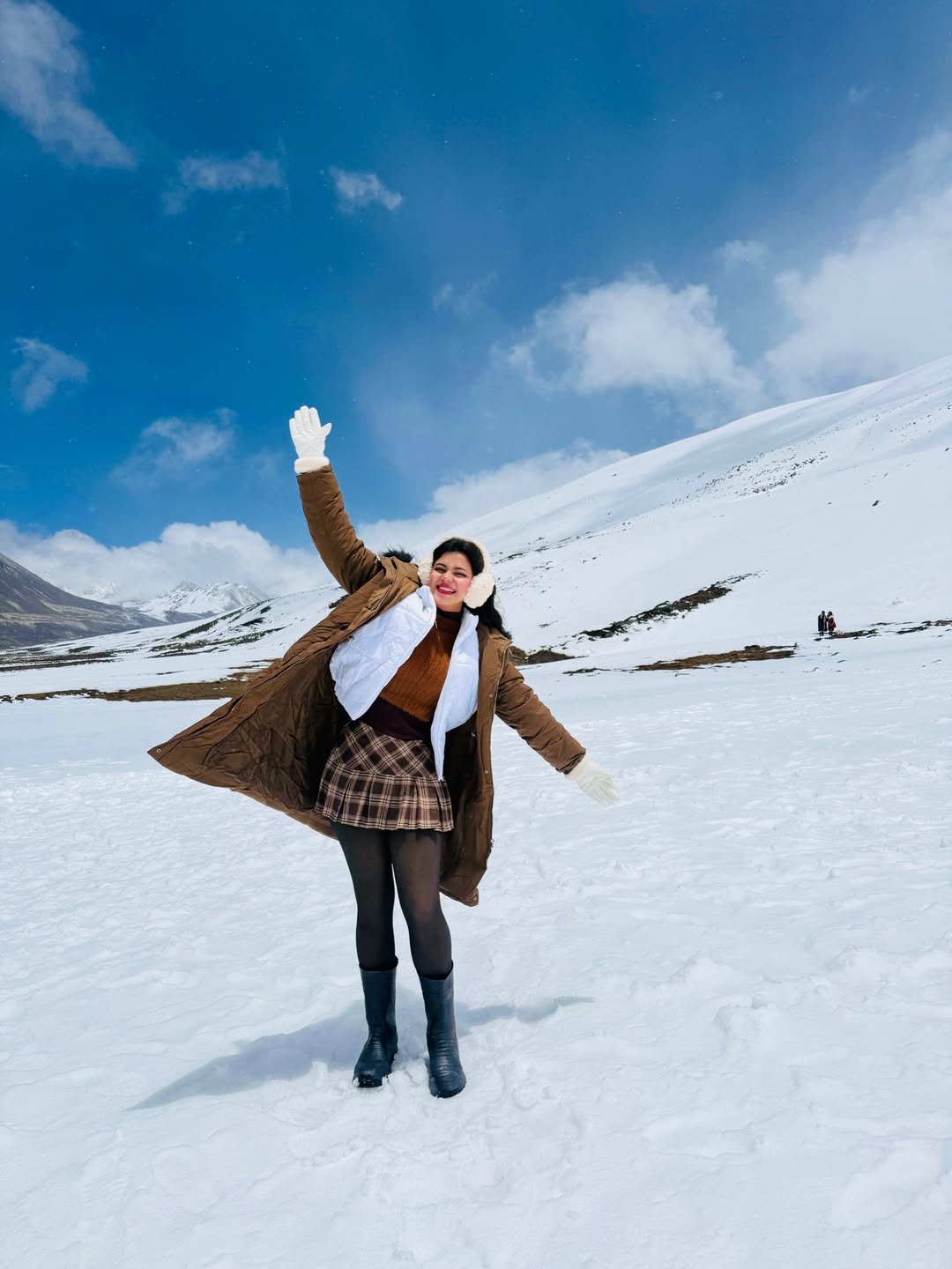 Caramel Winter Parka with Plaid Pleated Skirt, White Puffer Vest, and Cream Earmuffs