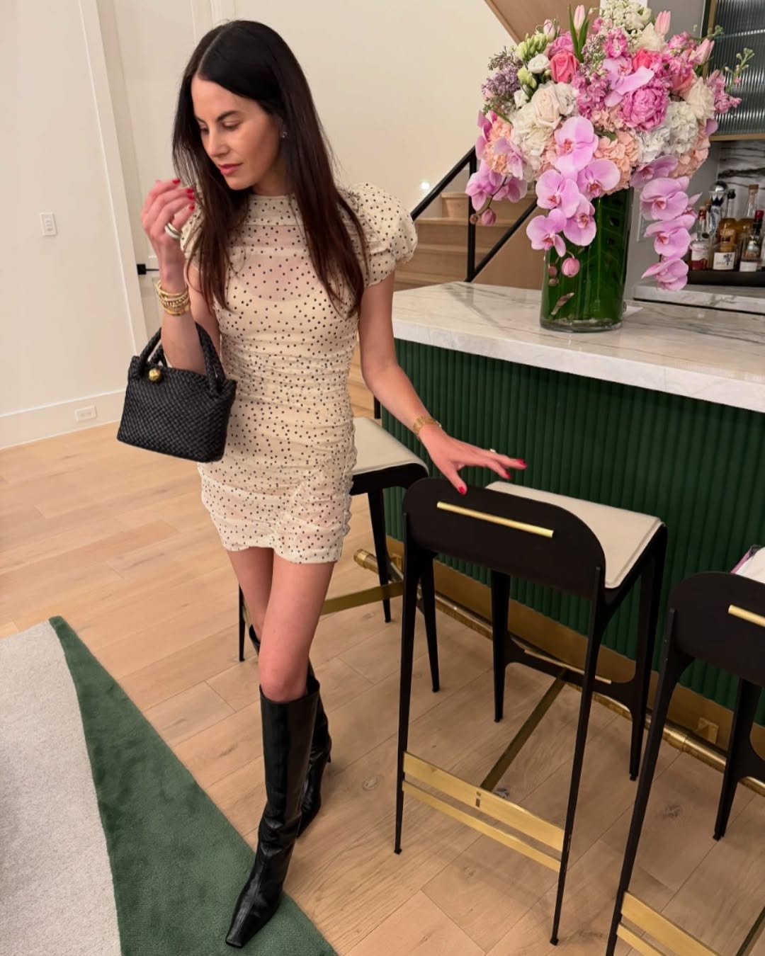 Cream Polka-Dot Ruched Dress with Black Knee-High Leather Boots by a Fluted Green Bar