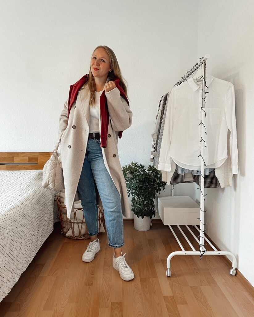 Draped Red Knit over Grey Overcoat and Mid-Wash Denim