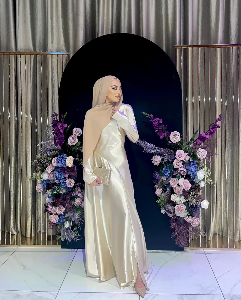 Ivory Satin Gown with Hijab and Floral Arch Backdrop at Indoor Gala