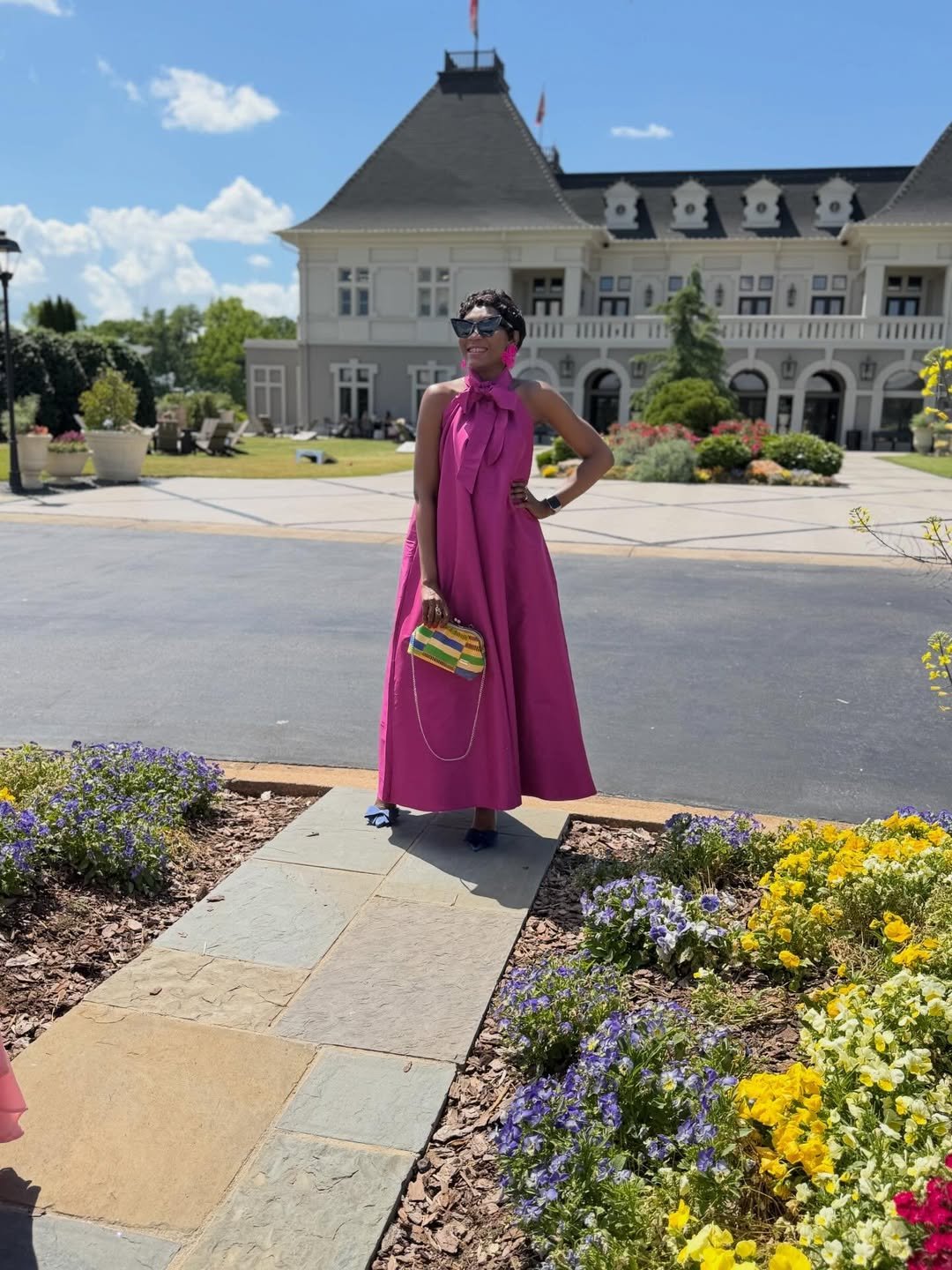 Orchid Pink Halter Maxi Dress with Striped Clutch outside a Country Club Estate