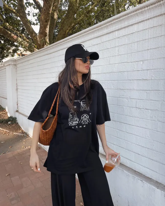 Oversized Black Graphic Tee with Wide Leg Pants and Woven Brown Bag