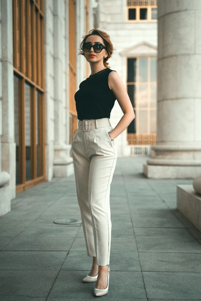 Sleeveless Black Top with High-Waist Beige Trousers and Bold Sunglasses