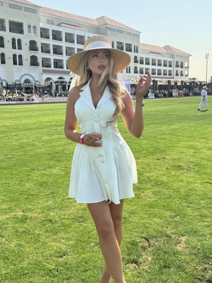 Sleeveless White Mini Dress with Straw Hat and Champagne Glass at Polo Club Lawn