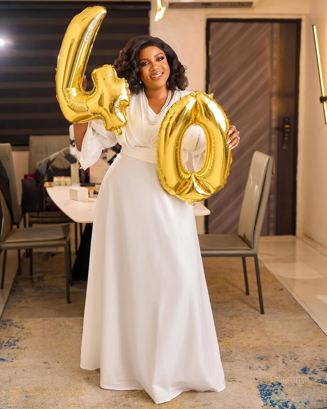 White Draped Gown with Pearl Necklace and Gold Balloons over a Distressed Area Rug