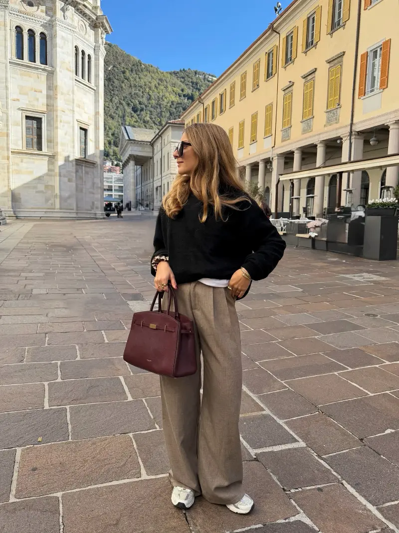Black Crewneck Sweater with Tailored Taupe Trousers, White Sneakers, and Burgundy Handbag
