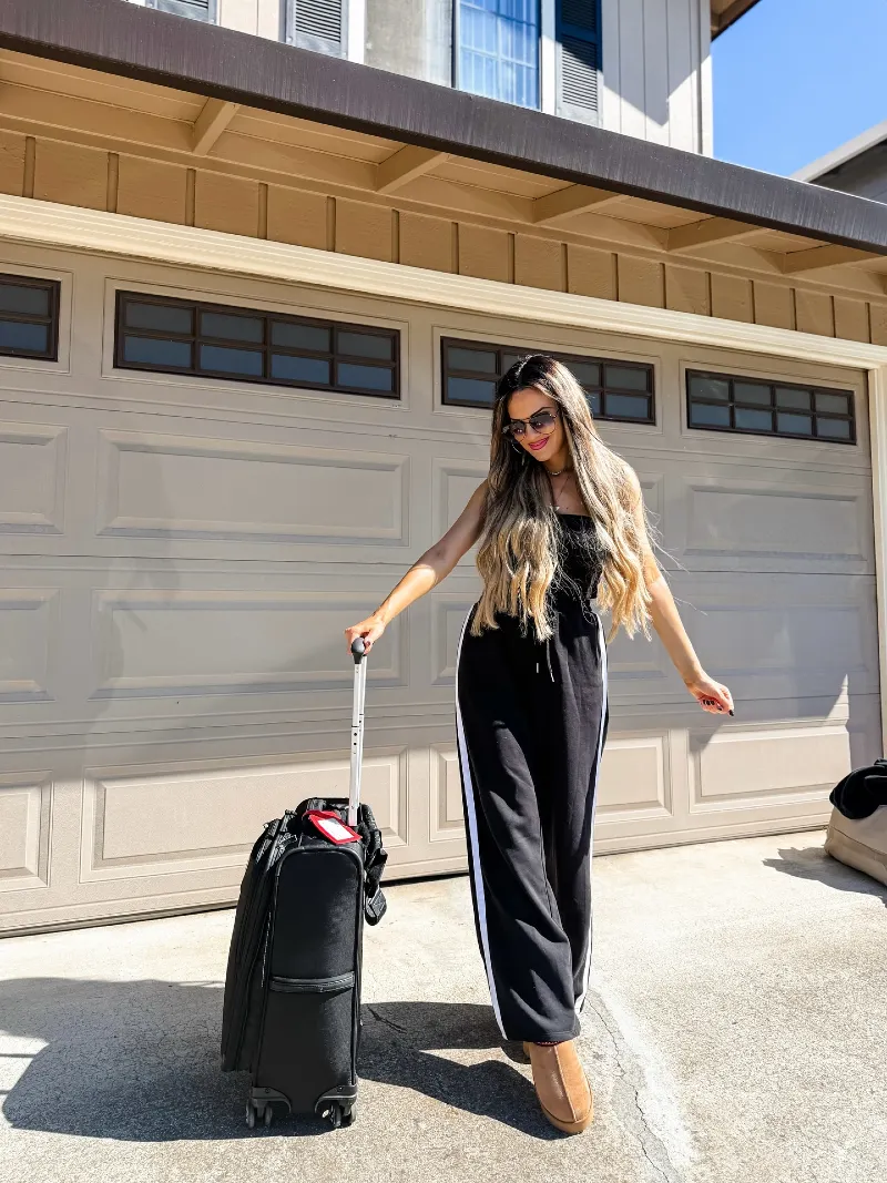 Black Track Pants with White Side Stripes, Tube Top, and Rolling Luggage