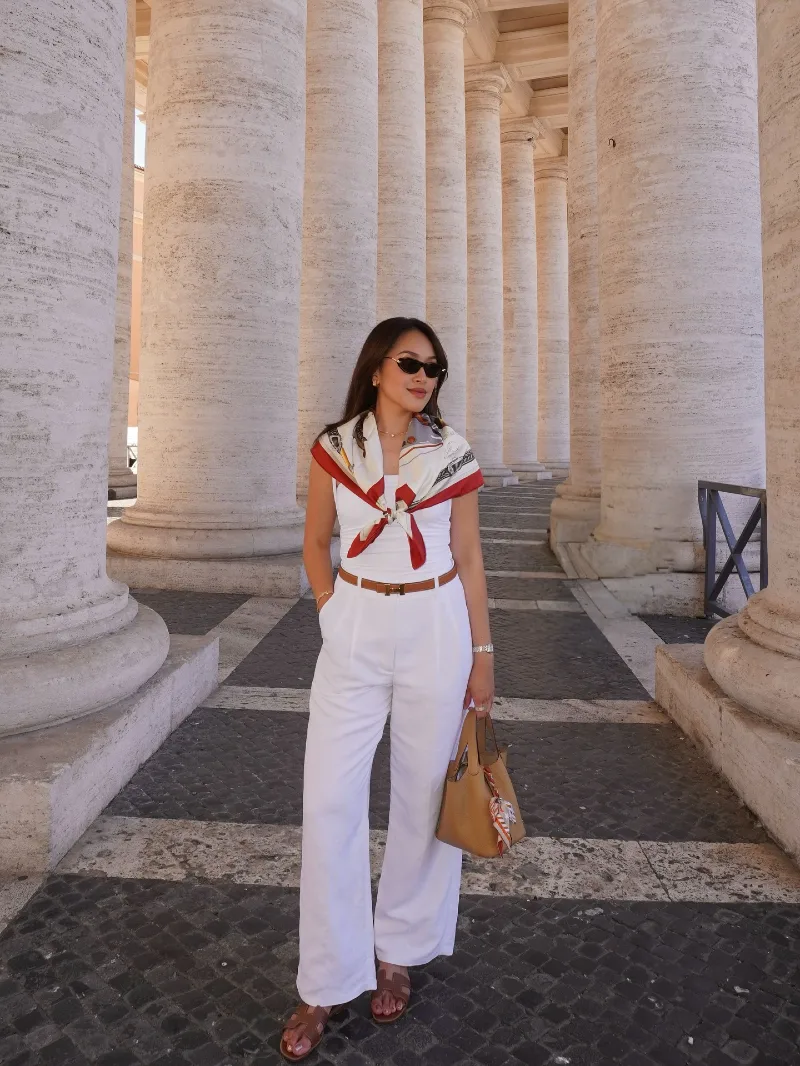 Crisp White Wide-Leg Trousers with Silk Scarf and Cognac Leather Slides in Front of Roman Colonnades