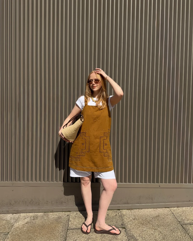 Embroidered Ochre Tunic Layered Over a White Tee and Shorts with a Woven Straw Tote