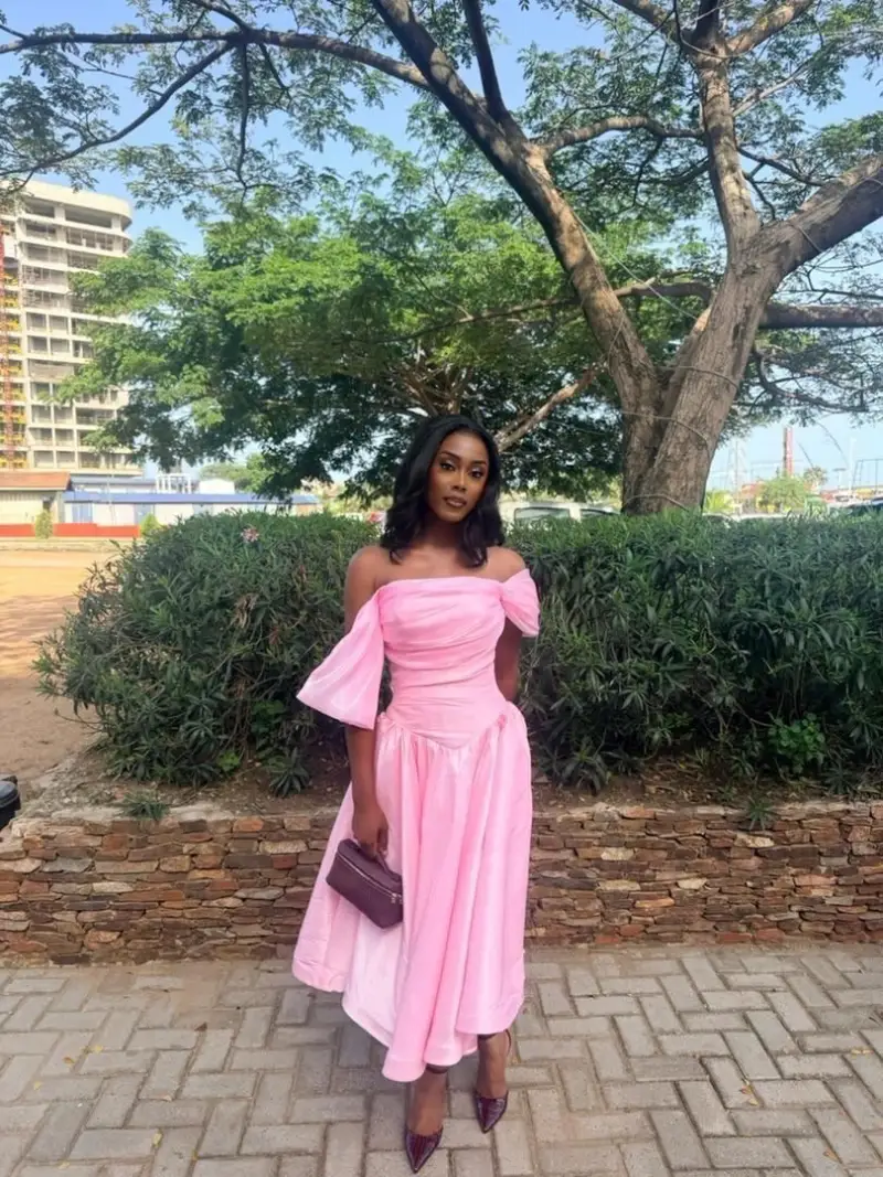 Pastel Pink Off-the-Shoulder Midi Dress with Dramatic Sleeve Detail and Dark Accessories