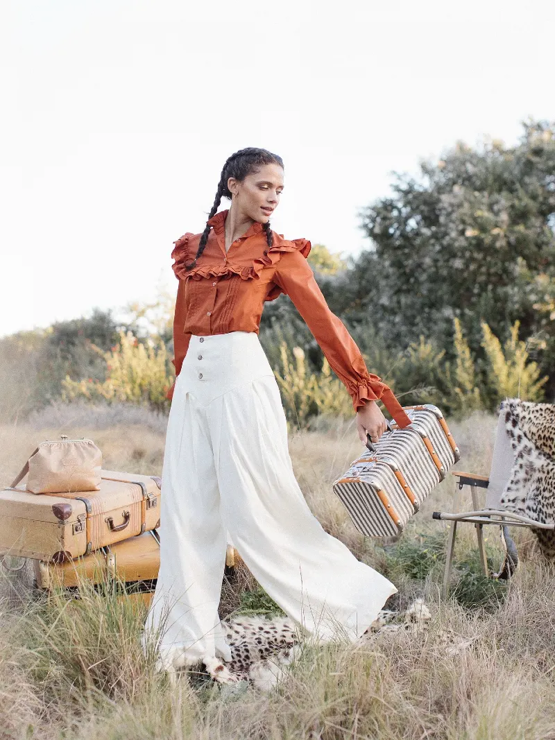 Rust Ruffle Blouse with High-Waisted Ivory Palazzos and Vintage Suitcase