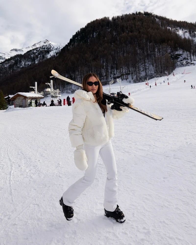 White Puffer Jacket with White Ski Pants, Mittens, and Skis